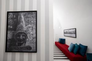 un soggiorno con divano rosso e un dipinto di Pulcinella Suite a Napoli