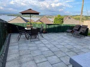 een patio met een tafel en stoelen en een parasol bij Superb base for exploring Cornwall and Plymouth in Saltash