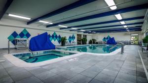 a large swimming pool with blue chairs in a building at Holiday Inn & Suites Syracuse Airport - Liverpool by IHG in Liverpool