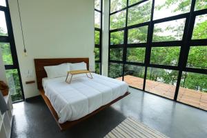 a bedroom with a large bed and large windows at The River Bank, Jinja in Jinja +15 photos