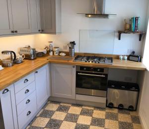 uma cozinha com armários brancos e um forno com placa de fogão em 3 Bedroom Cottage, Red Wharf Bay, Pentraeth, Anglesey em Pentraeth