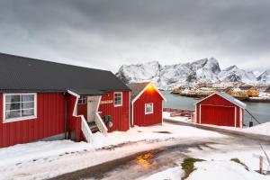 a red building with mountains in the background at Anitas Waterfront Cabins in Reine