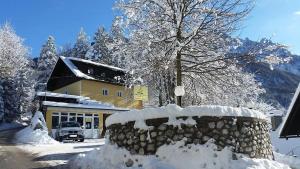 a house with a stone wall covered in snow at Rooms Barovc by the Lake Jasna in Kranjska Gora
