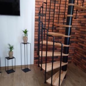 spiralne schody obok ściany z cegły z dwoma stolikami bocznymi w obiekcie Apartament w Pieninach w Krościenku