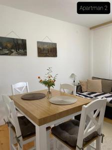 a dining room table with white chairs and a couch at Apartmani Jarevac in Bajina Bašta +3 photos