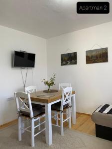 a dining room table with white chairs and a tv at Apartmani Jarevac in Bajina Bašta
