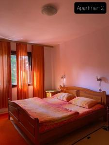 a bedroom with a large bed with orange curtains at Apartmani Jarevac in Bajina Bašta