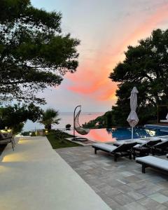a pool with benches and an umbrella and a sunset at Pino Boutique Hotel in Ulcinj