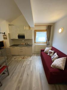 a living room with a red couch and a kitchen at CASA LOLA in Falcade