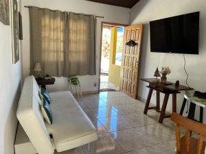 a living room with a white couch and a television at CASA BUZIOS PRAIA RASA in Búzios