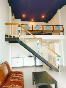 a staircase in a living room with a couch and a table at The Beach Resort & Residence - SHA Plus in Pathiu