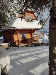 a log cabin with snow on top of it at Domki Szwajnosówka in Witów