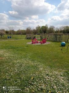 park z czerwonymi krzesłami na polu trawy w obiekcie Bungalow la Bohémienne w mieście Oissel
