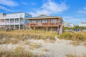 a house on the beach next to the sand at Charisma in Holden Beach