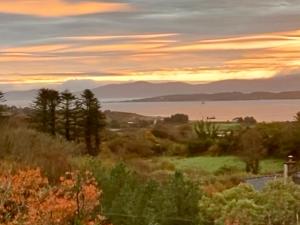 einen Sonnenuntergang über einem Feld mit Bäumen und einem Wasserkörper in der Unterkunft Rodeen self-catering apartment in Castletownbere