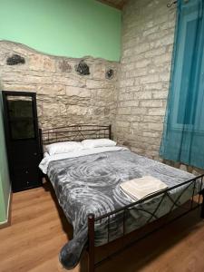een bed in een kamer met een stenen muur bij Zouglas App Guesthouse in Limassol