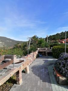 park z ławkami i kwiatami na wzgórzu w obiekcie Appartamento vista mare con terrazza Bosa Turas w mieście Magomadas