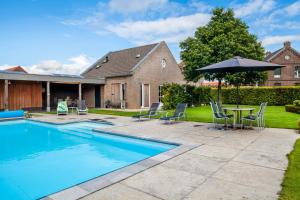 a swimming pool with a table and chairs and an umbrella at B&B La Vita Verde in Susteren