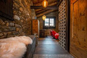 a hallway with a stone wall and a red couch at JAT MOUNTAIN HOUSES - Casa Pairal Jarca - dúplex - a 1 km de Canillo in Canillo