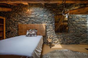 a room with a bed in a stone wall at JAT MOUNTAIN HOUSES - Casa Pairal Jarca - dúplex - a 1 km de Canillo in Canillo