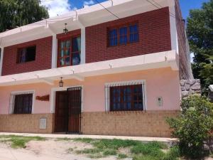 una casa con ventanas azules y un ladrillo en Imaynalla Humahuaca Hostl, en Humahuaca