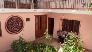 a woman sitting on a bench outside of a house at Imaynalla Humahuaca Hostl in Humahuaca