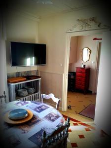 uma sala de estar com uma mesa e uma televisão na parede em B&B chez Annie em Saint-Martin-de-Gurçon