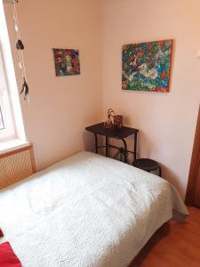 a bedroom with a white bed and a table at Garden house in Daugavpils