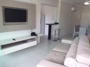 a living room with a white couch and a tv at Residencial Green Village in Ubatuba