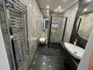 a bathroom with a sink and a shower and a toilet at Apartament LuxLook in Nowy Sącz