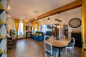 a living room with a table and a clock on the wall at La Suite de Chantilly - Appartement de 80m2 avec Jacuzzi privé ! in Chantilly
