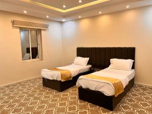 two twin beds in a room with a window at فيلا كارمة in Al Madinah