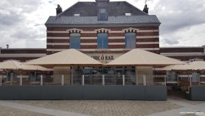 un bâtiment avec des parasols en bronze devant lui dans l'établissement Chic'o Rail, à Saint-Omer