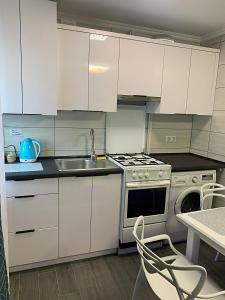 a kitchen with white cabinets and a sink and a stove at Зручні апартаменти подобово! Центр. Руська. 3 кімн. in Ternopilʼ