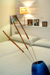 Un jarrón azul con palos al lado de una cama en Hotel Mar de Tasmània - Auto Check-in en La Bisbal