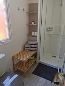 a bathroom with a shower and a wooden bench next to a shower at Mobile Home Rock 'n' Sea in Sveti Juraj