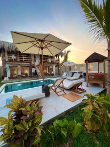 uma piscina com duas espreguiçadeiras e um guarda-sol em Casa Bali Vichayito em Vichayito