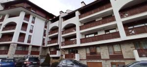 an apartment building with cars parked in front of it at Free SPA Pirin lodge cosy apartment in Bansko