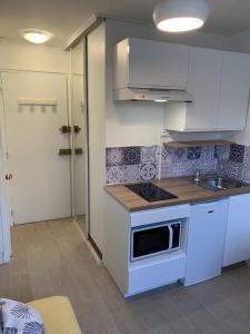 a white kitchen with a stove and a sink at Studio Cosy in Wissant