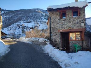 a stone building with snow on the side of a road at Casa Pirineu in Esterri de Cardós