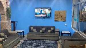 una sala de estar con 2 sofás y una pared azul en City Center Hostel en Áqaba