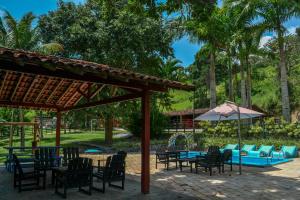 a patio with tables and chairs and an umbrella at Chácara Maluco Beleza 1 in Chã Grande
