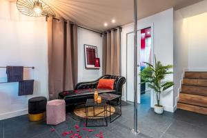 a living room with a black leather couch and a table at LoveSparadise - Suite L'élixir in Chessy