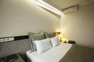 Schlafzimmer mit einem Bett mit weißer Bettwäsche und Kissen in der Unterkunft Kadıköy Rıhtım Hotel in Istanbul
