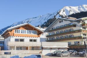 un hôtel avec des voitures garées dans un parking en face d'une montagne dans l'établissement Haller´s Posthaus, à Riezlern