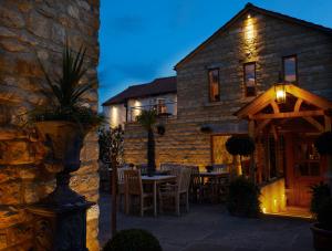 Una casa de piedra con una mesa y sillas delante de ella. en The Farrier, en Scarborough