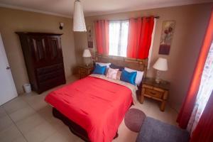 a bedroom with a red bed and a window at Fortescue Cherry Blossom Apartments in Saint Philip