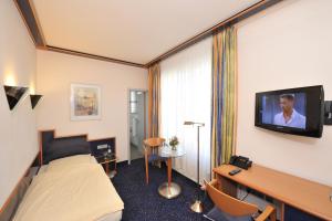 Habitación de hotel con cama y TV en la pared en Insel Hotel en Colonia