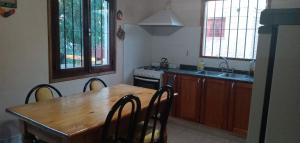 cocina con mesa de madera con sillas y fregadero en Chalet Los Molles en Villa Giardino