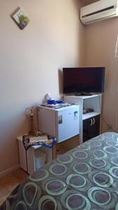 Zimmer mit einem Bett, einem Schreibtisch und einem TV in der Unterkunft Condomínio Sol de Verao in Florianópolis